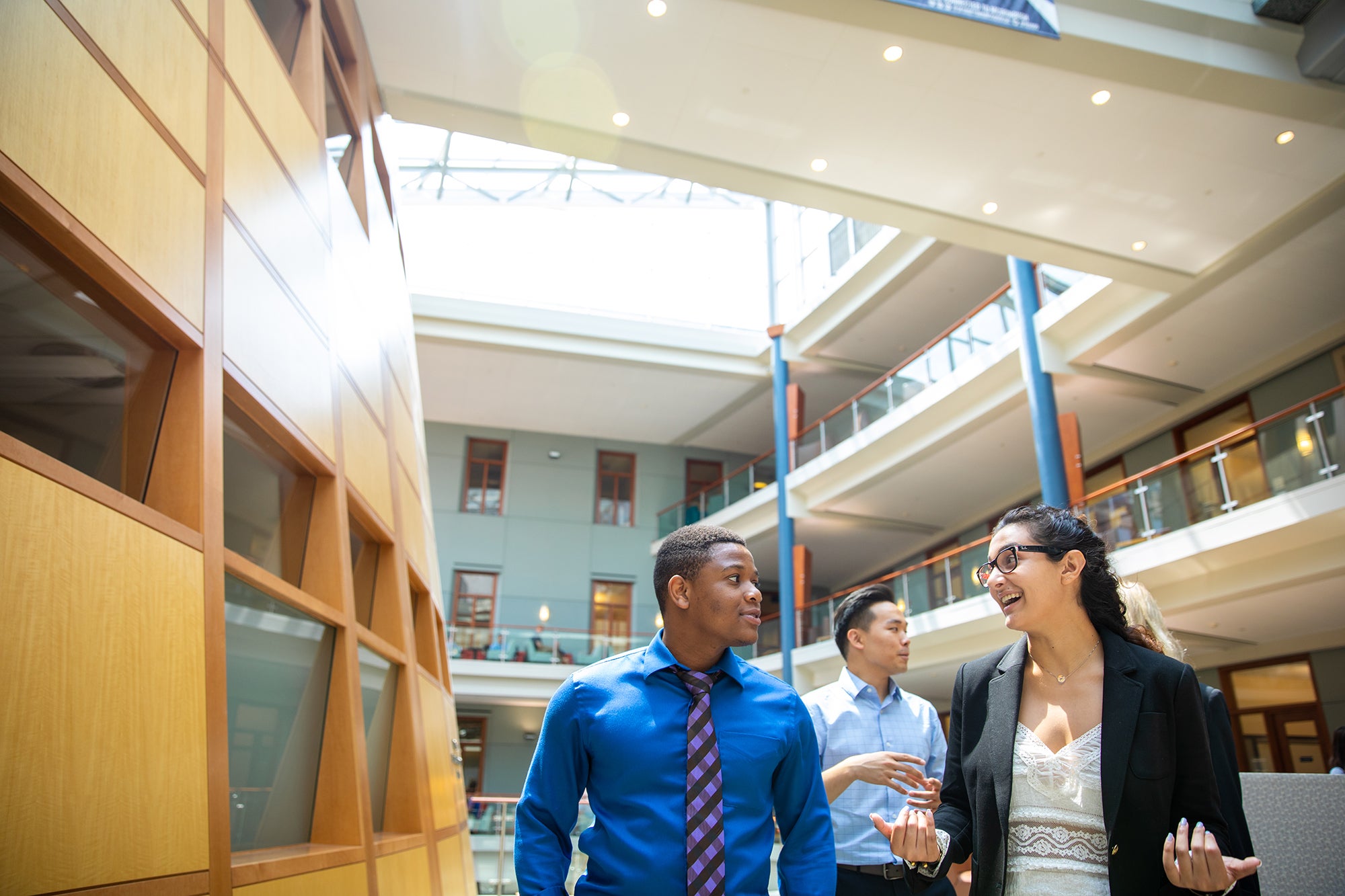 4 MiM Students talking and walking inside Hariri Atrium