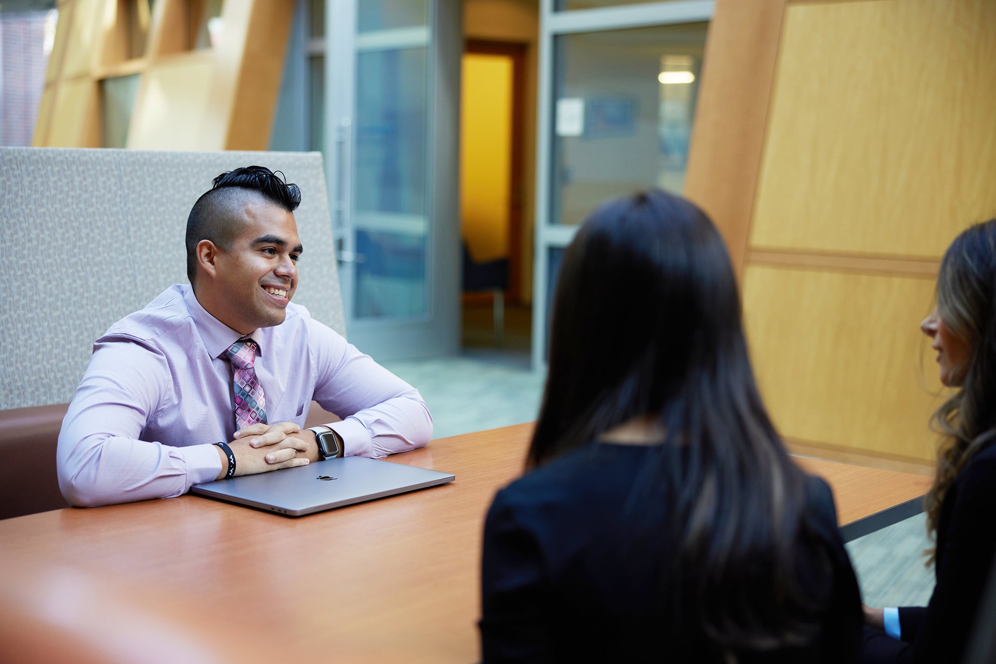 3 students sitting in a booth in Hariri
