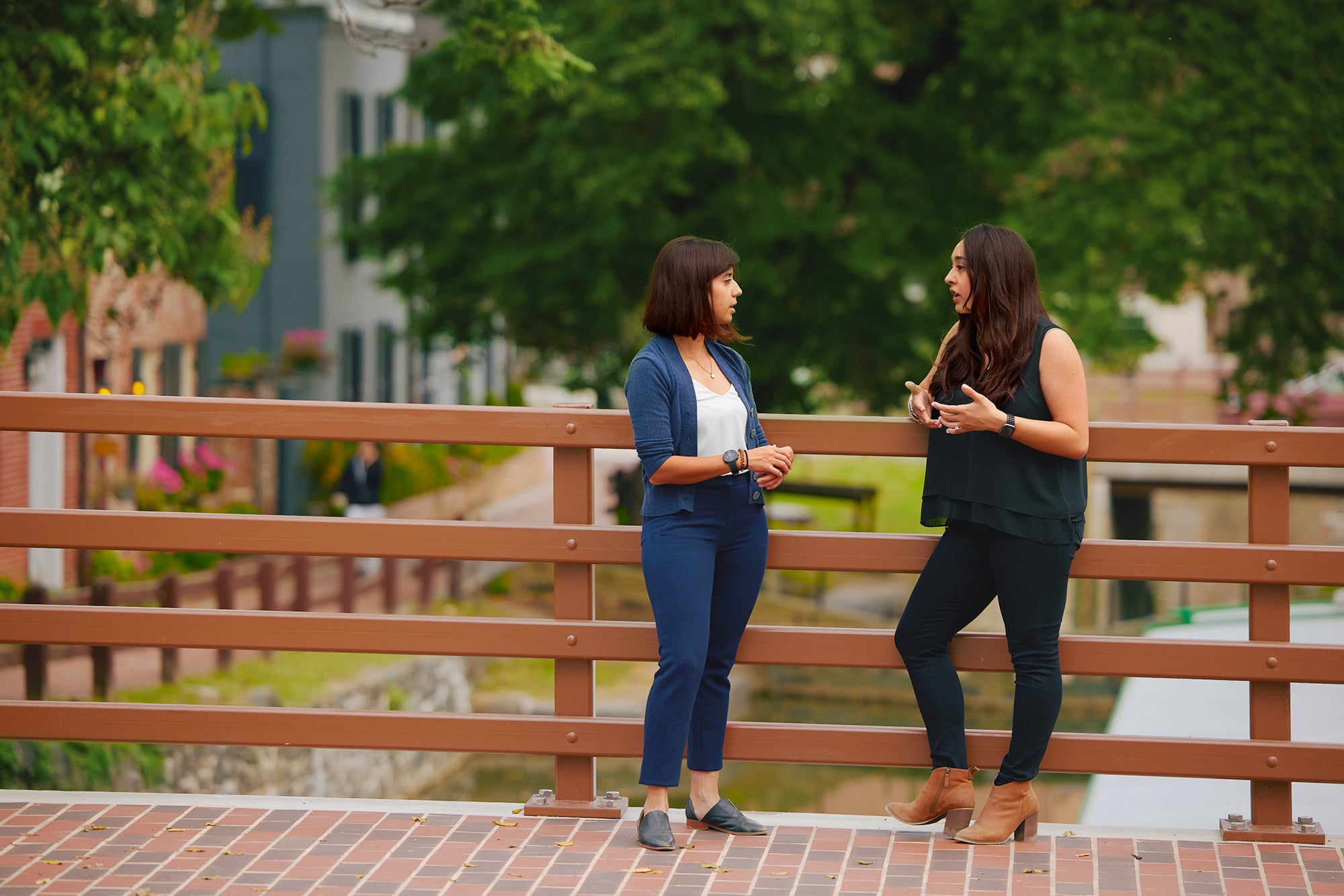 2 students talking on the bridge by the canal
