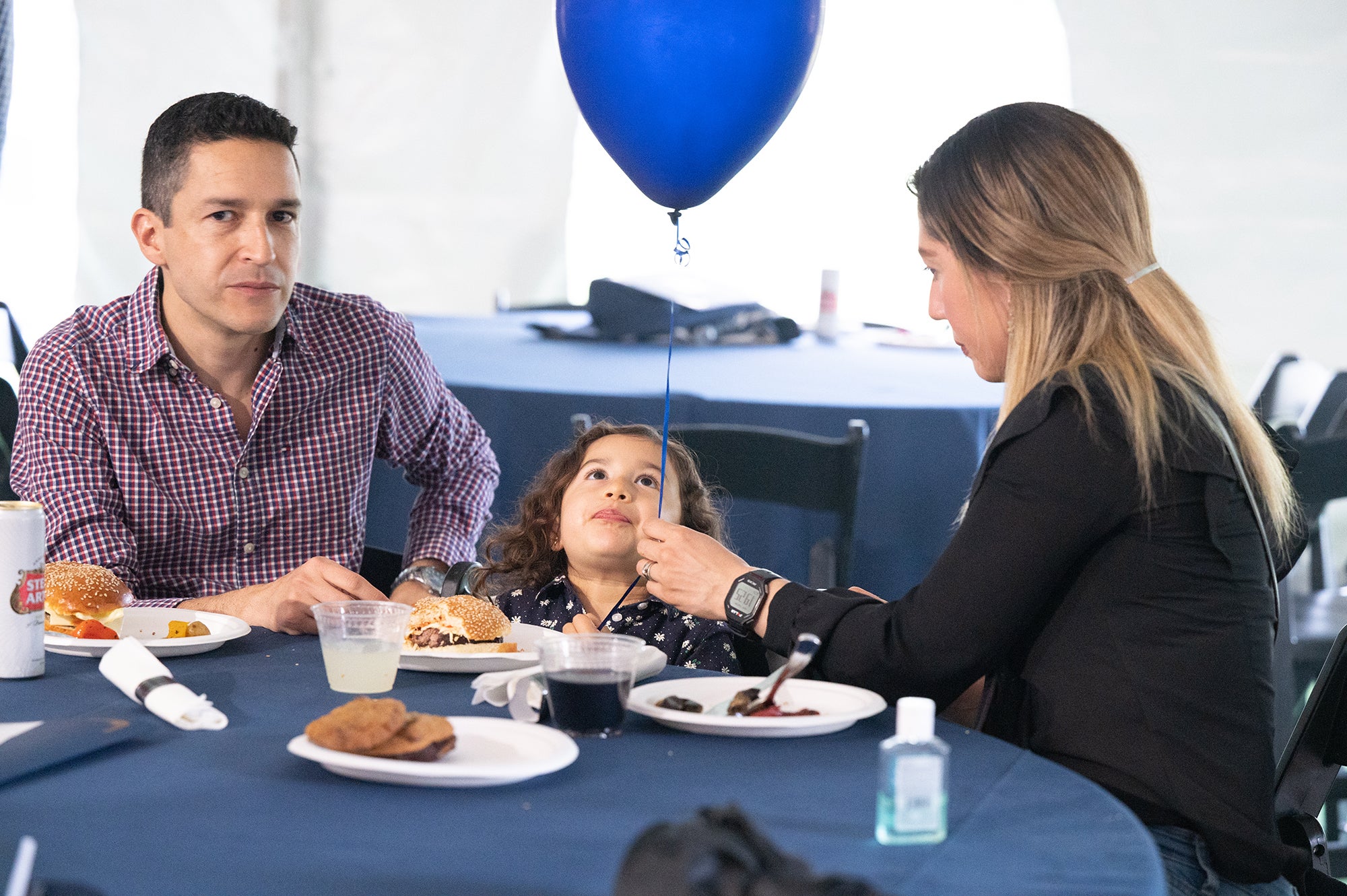 Parents sitting with child who is looking at a balloon