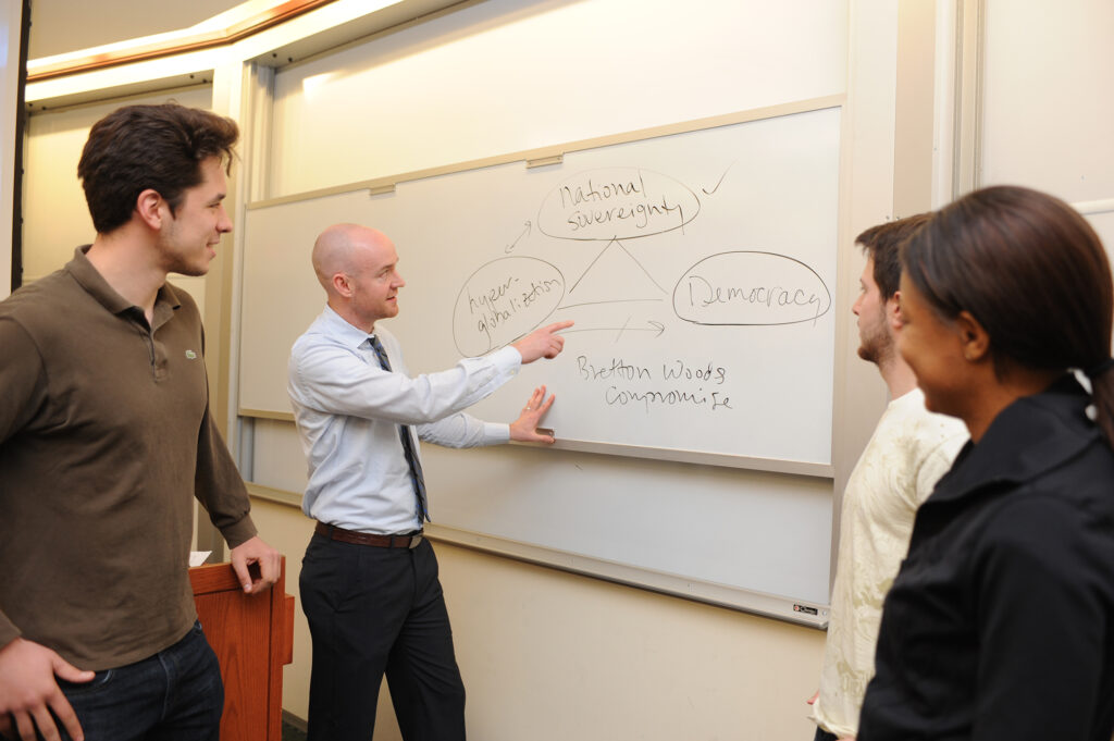 Professor Weymouth showing undergraduate students notes on a whiteboard