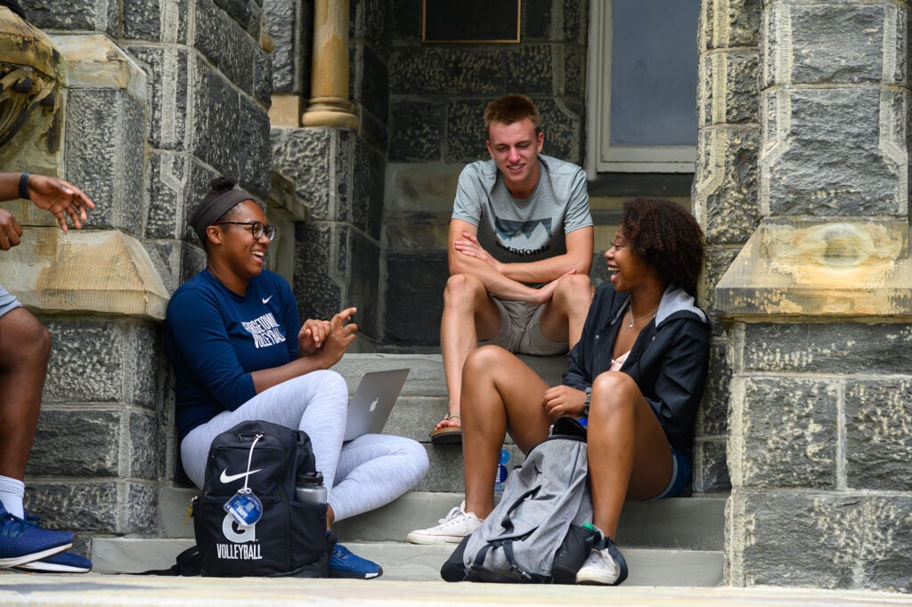 Georgetown University undergraduate business students sitting on the steps outside white gravenor building