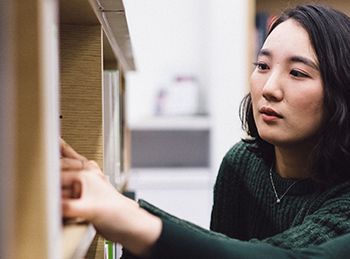 Undergraduate student looking at library shelf