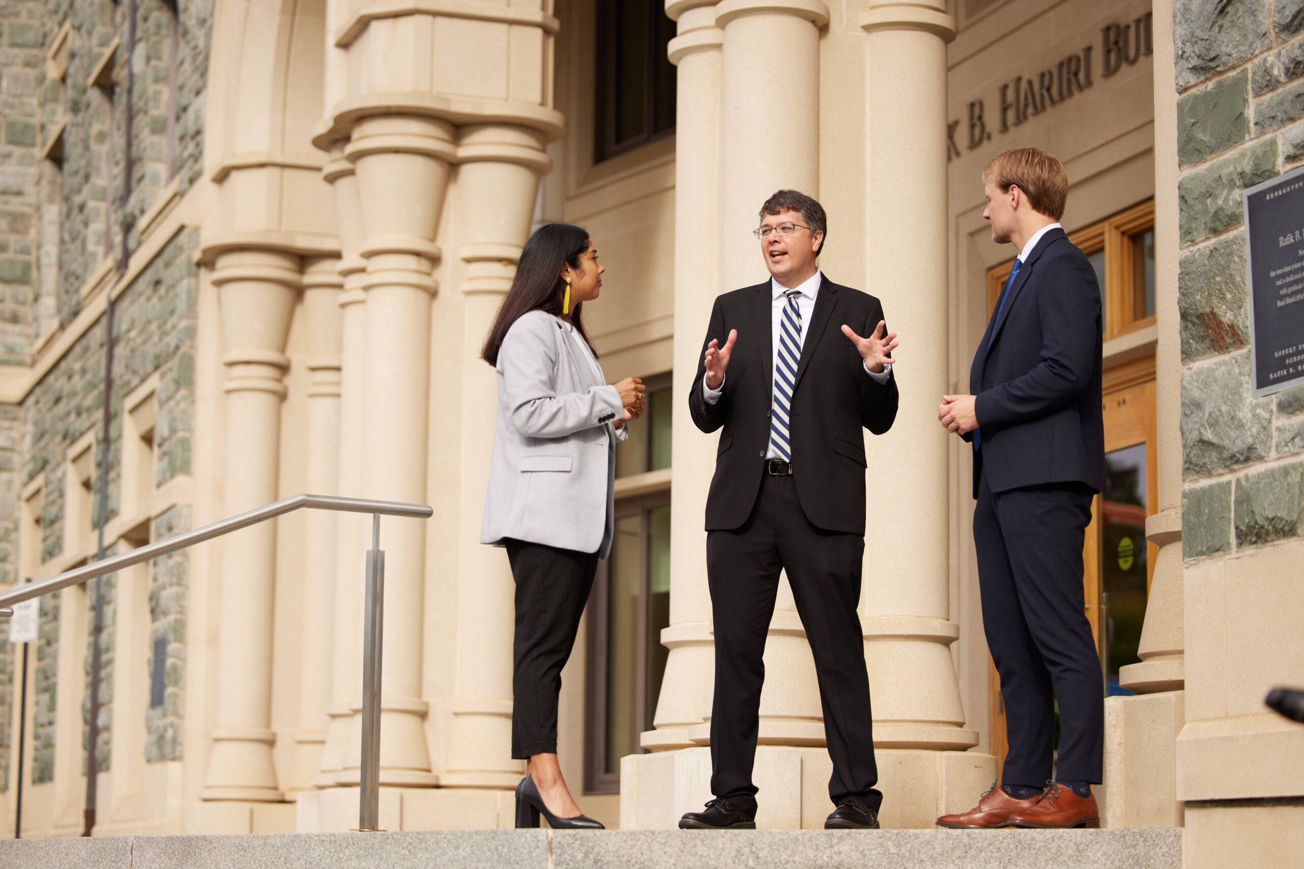 2 MiM students talking to program advisor outside Hariri