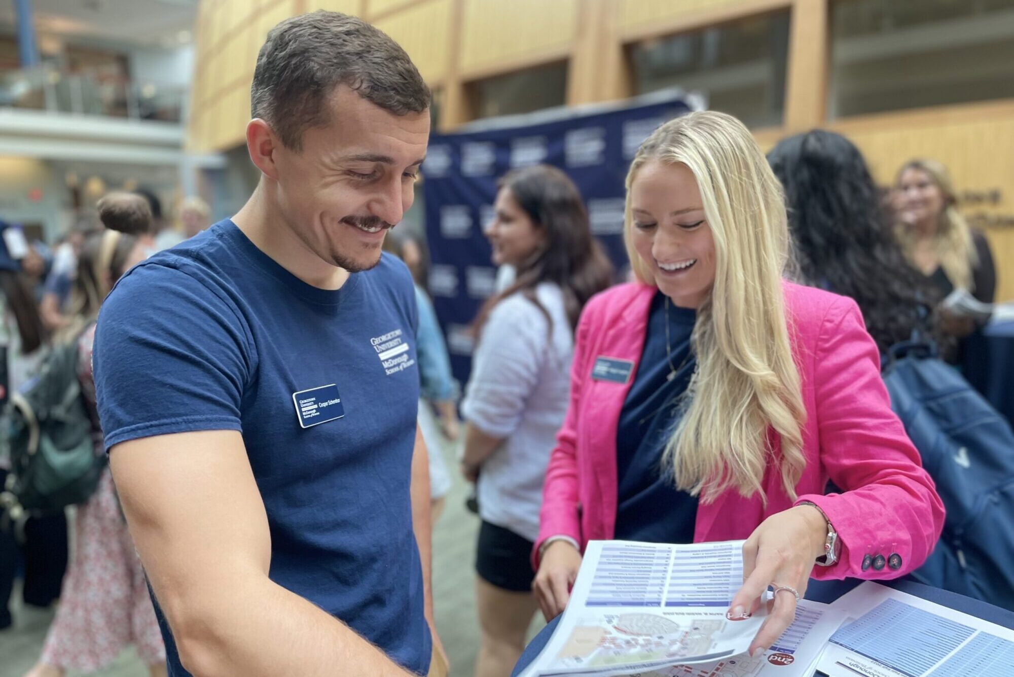 Two MBA students smiling at organization chart for student organization fair