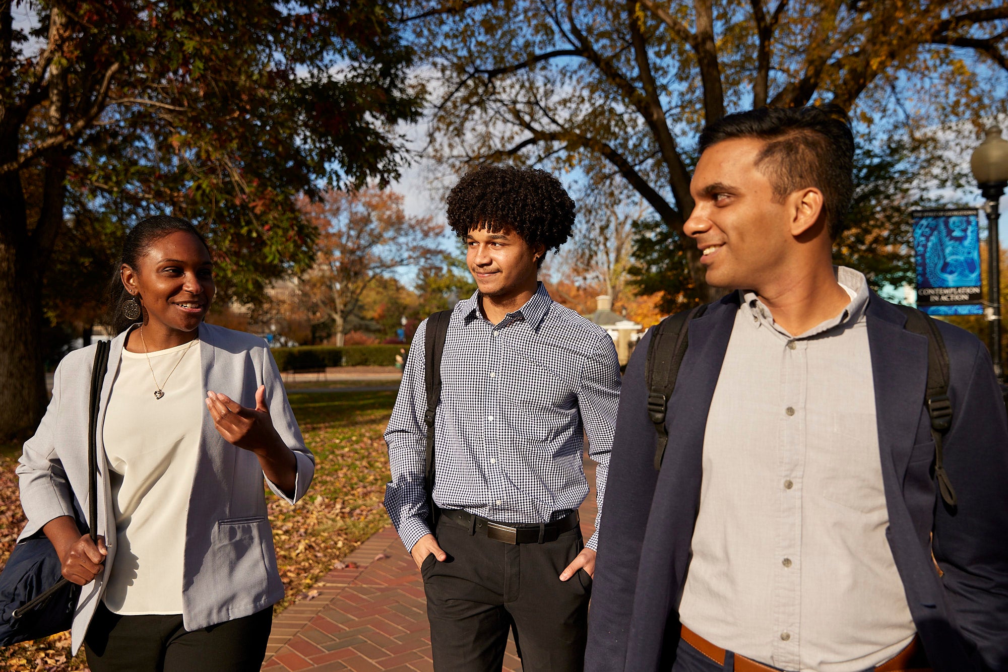 three students walking on campus in suits and with backpacks