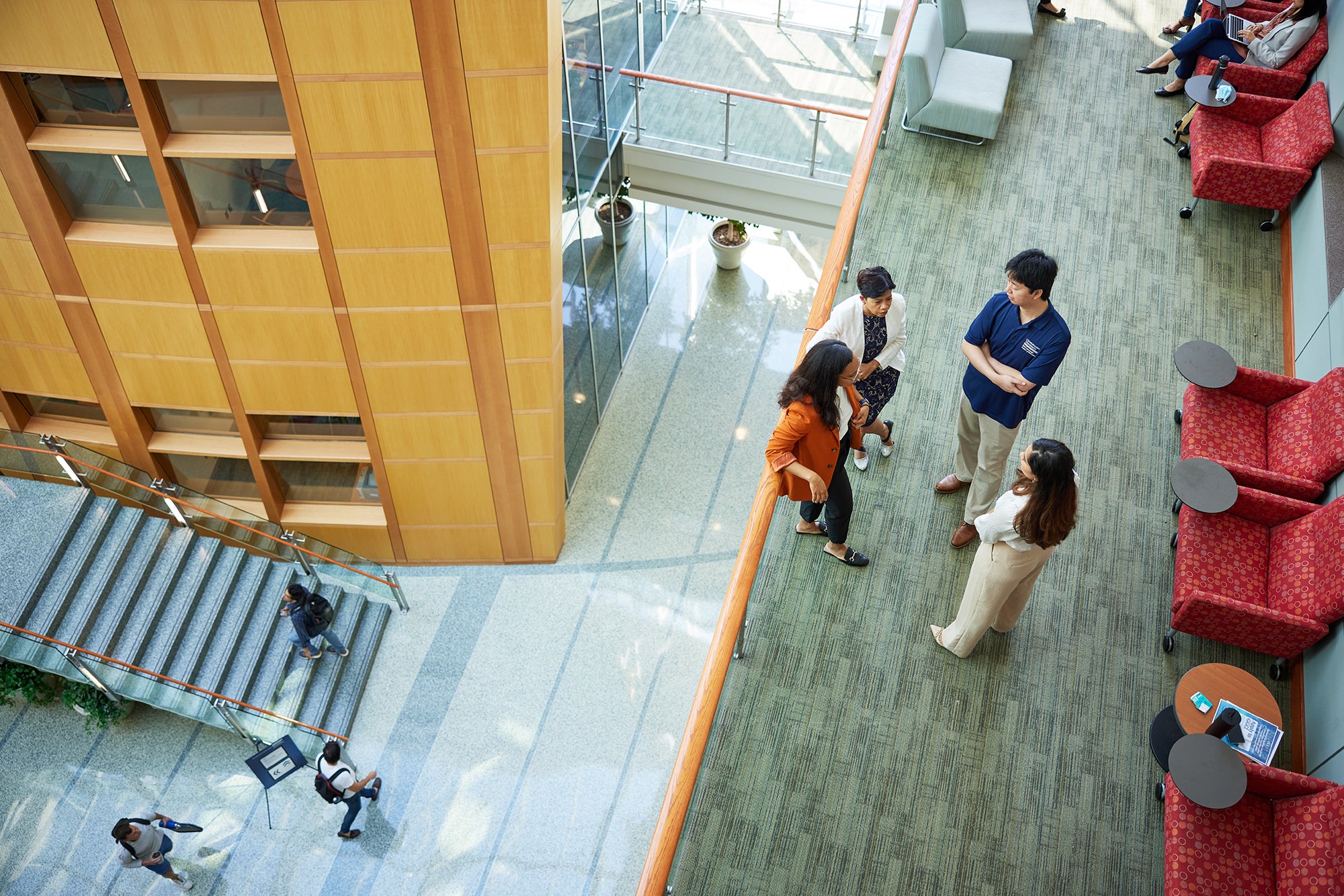 Overhead looking down at 3 MSBA Students laughing and talking with Sudipta in the Hariri Atrium