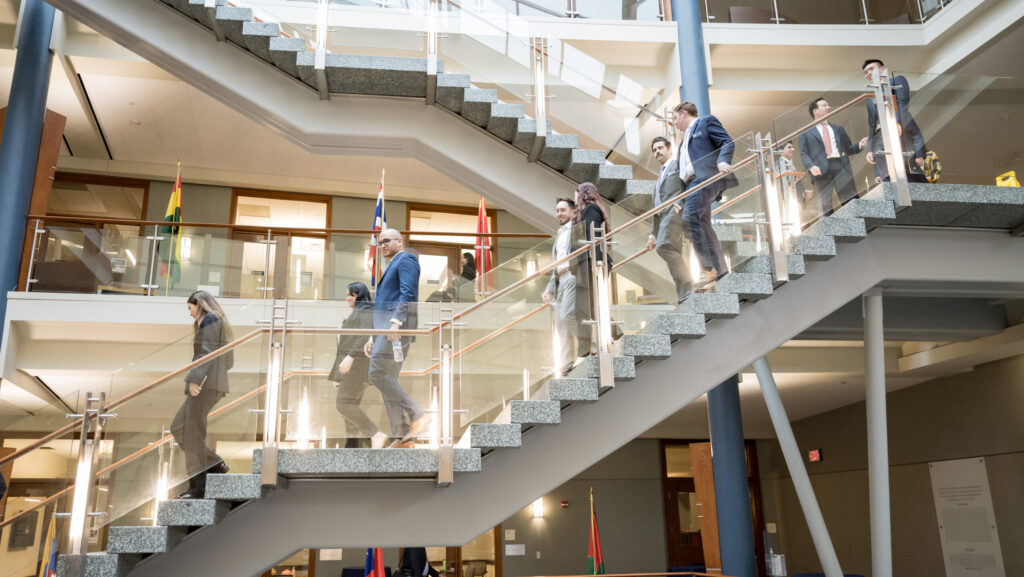Professional Custom Executive Education students in suits walking down the stairs in the Hariri Building, home of the McDonough School of Business