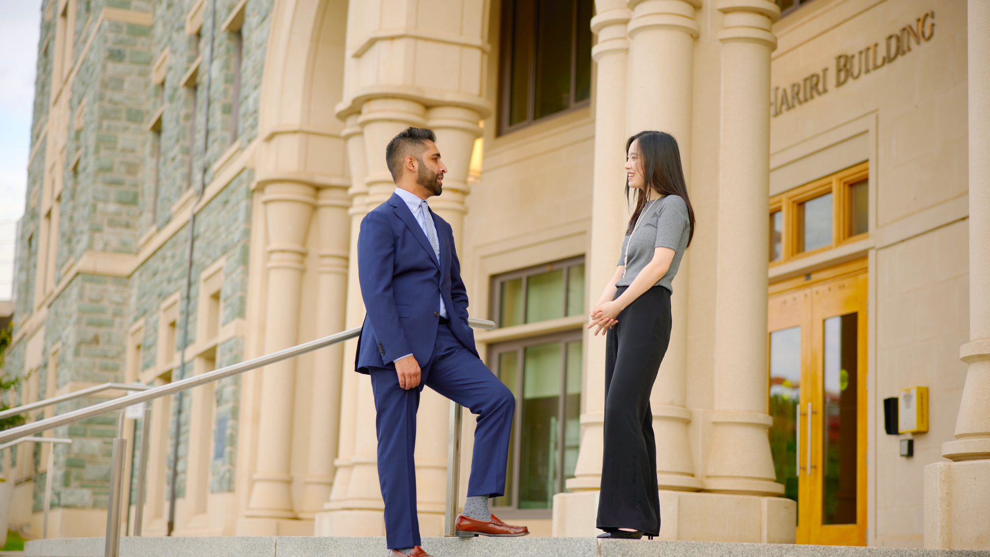 MBA students stand outside of the Rafik B. Hariri building in business attire