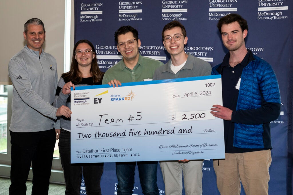 Mike Risk (EY) presents Team 5 (Costanza Rossi, Tony Mena, Joey Trigiani, and Luke Duffy) with a $2,500 check for winning the final round of the competition.