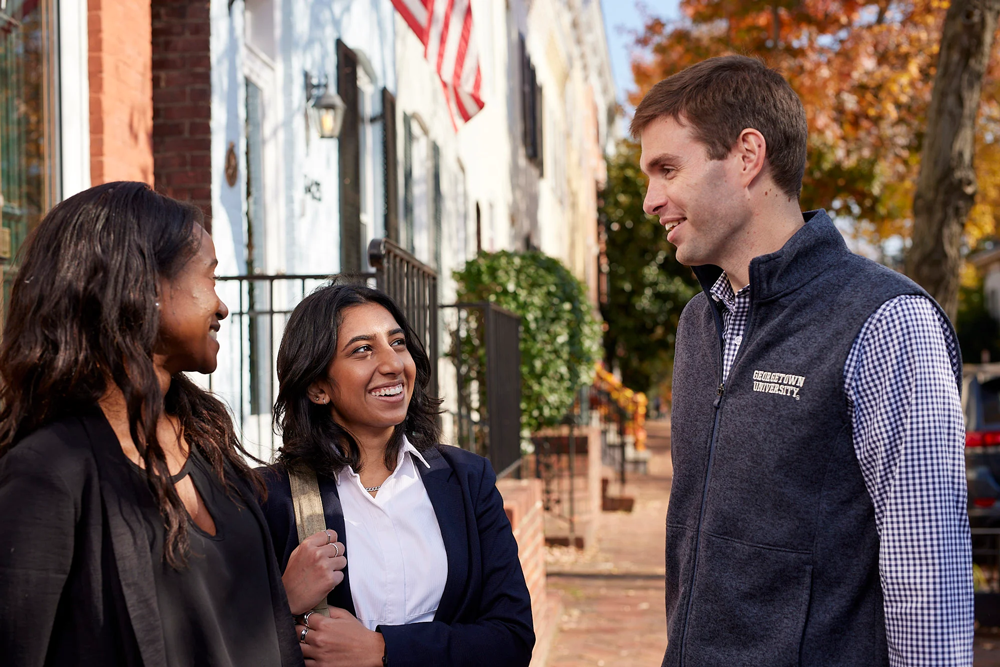 A student talking to two other people, charming and dazzling them with their Georgetown knowledge