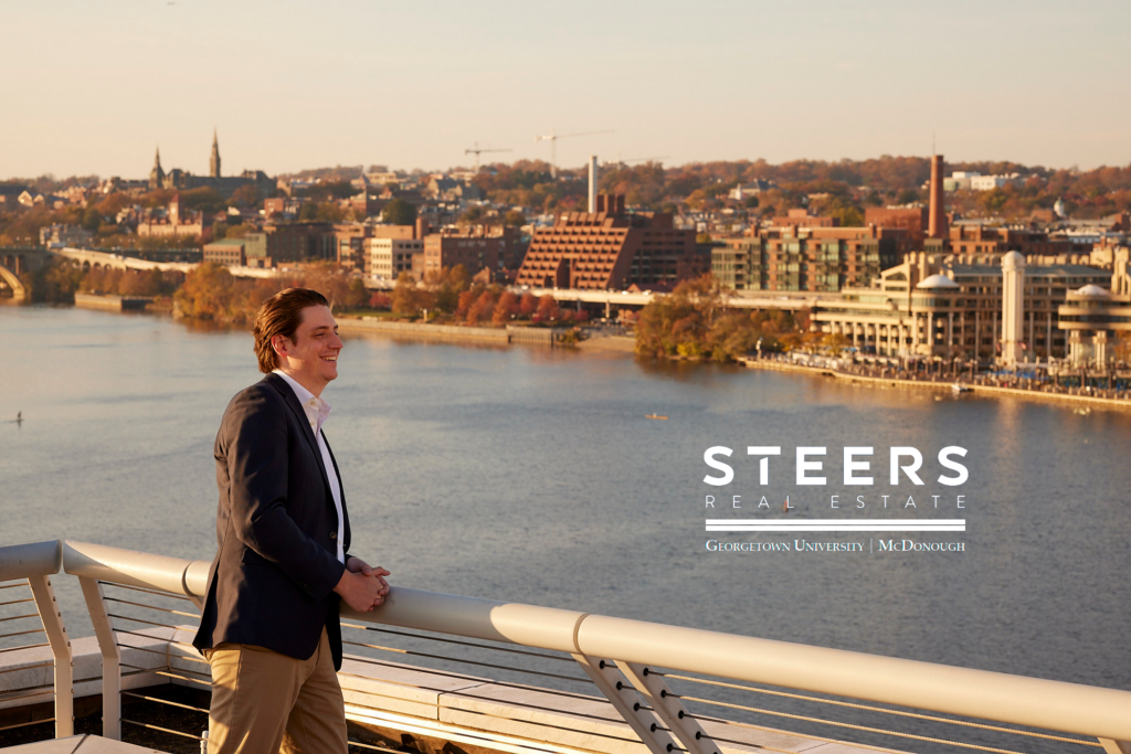 man standing looking over a river with the logo for the Steers Realestate logo overlaid