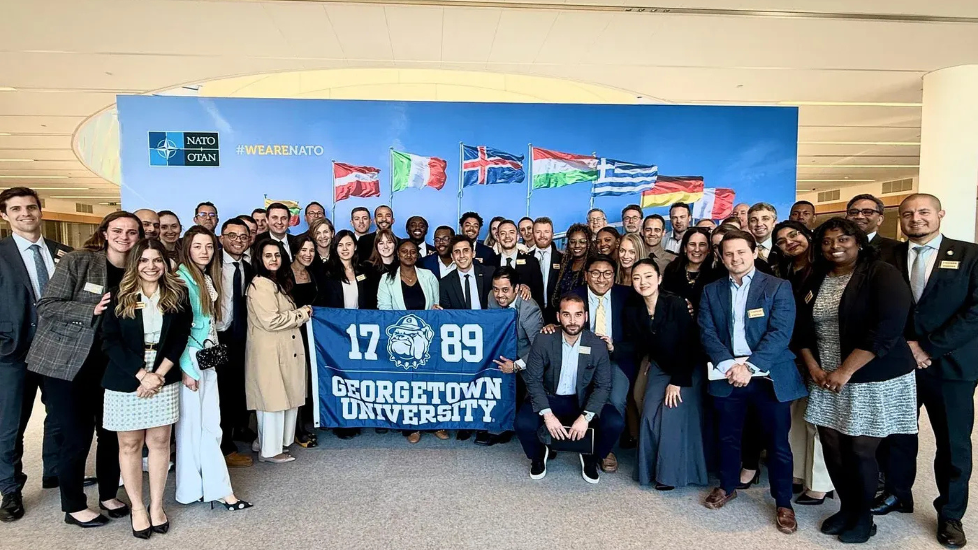 IBP students stand for a group photo holding a banner that reads