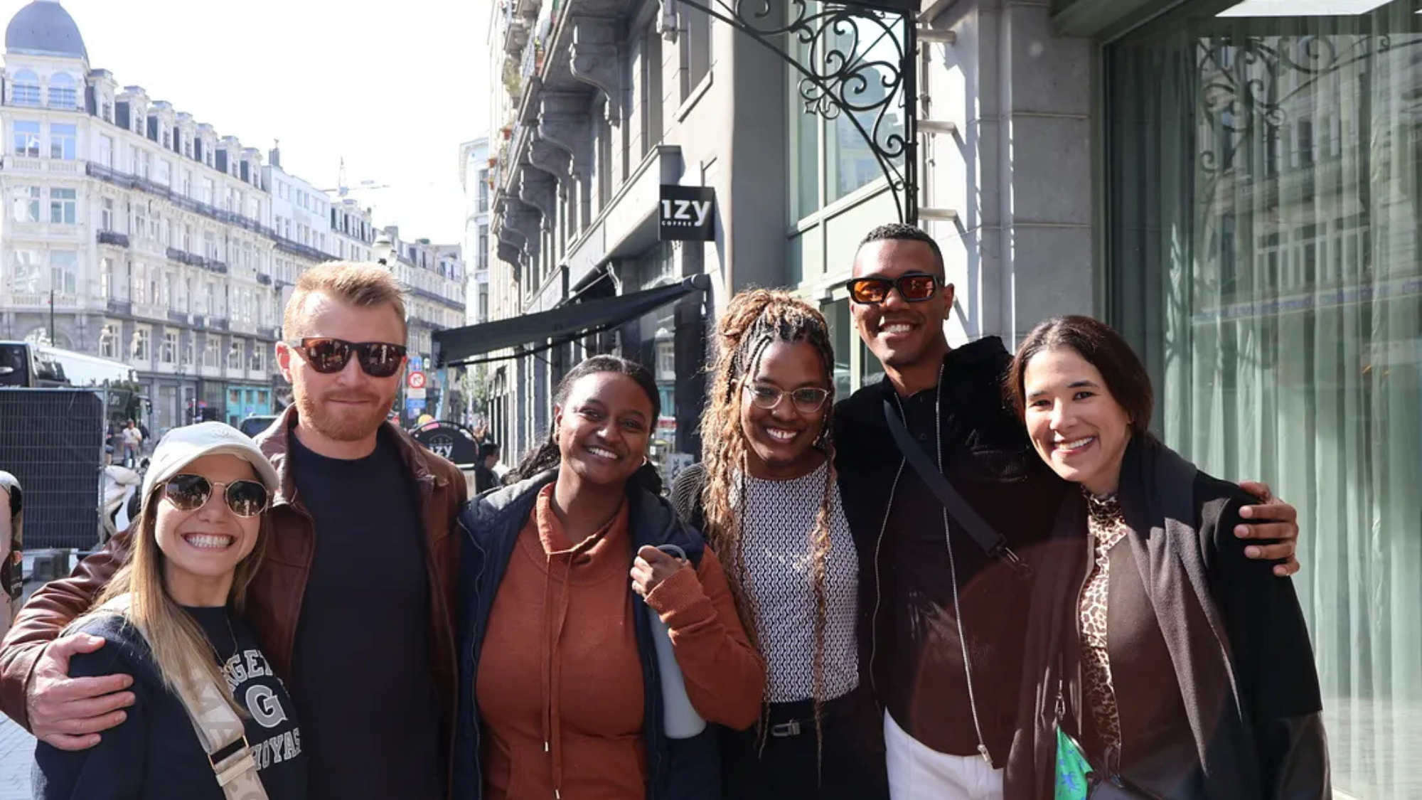 Five people of varying heights and descriptions pose for a group photo on a street in Brussels.