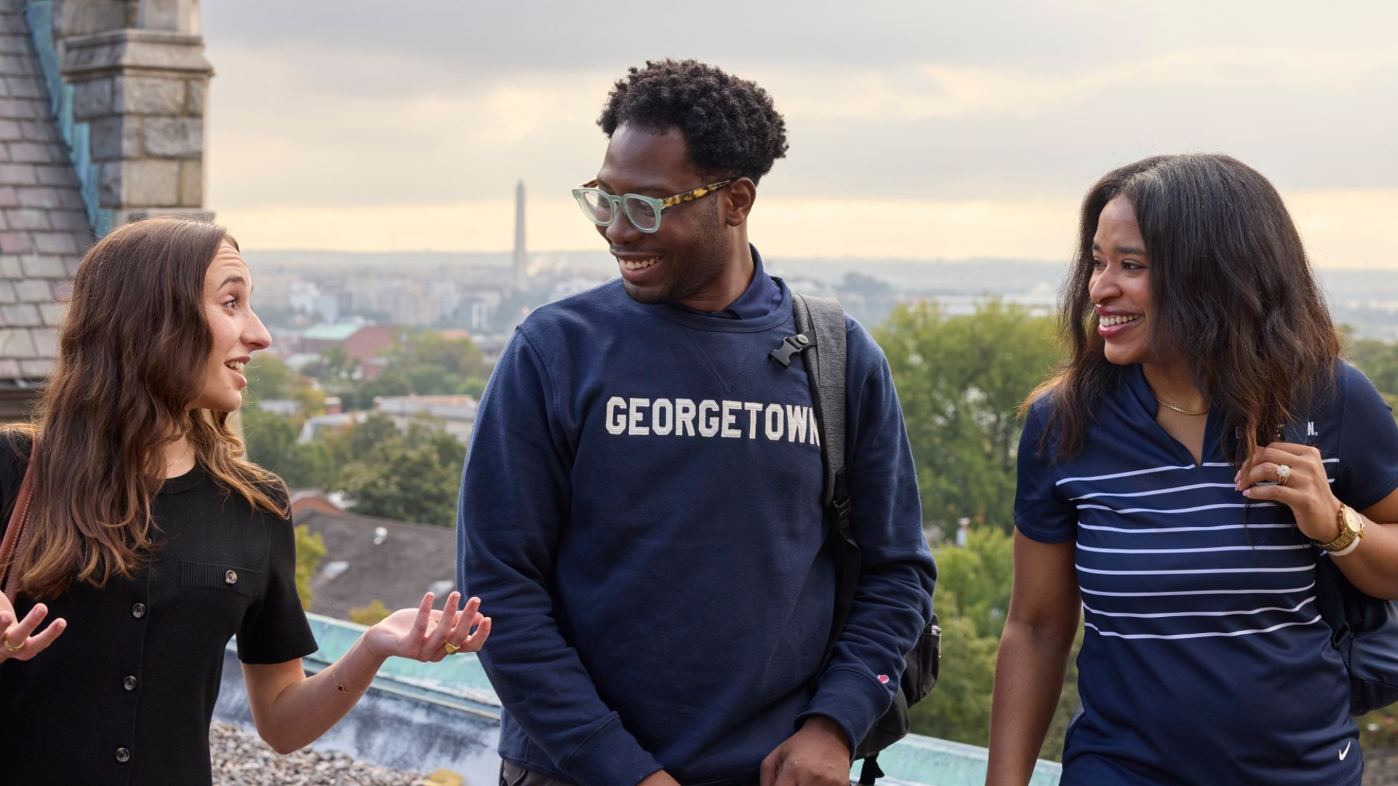 MBA students talking outside at Georgetown with the Washington Monument and D.C. landscape in the background