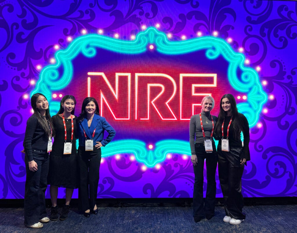 Group photo of Georgetown students and program director in front of NRF neon logo
