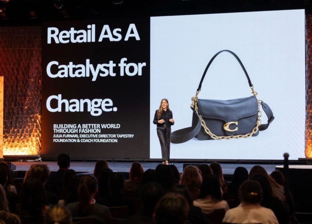 Julia Furnari on stage at NRF Foundation Student Program with slide that reads "Retail as a catalyst for change" behind them