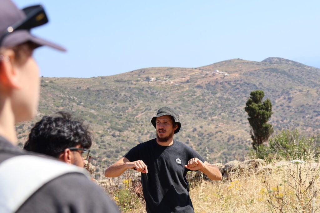 A guide explains to the class in the field.