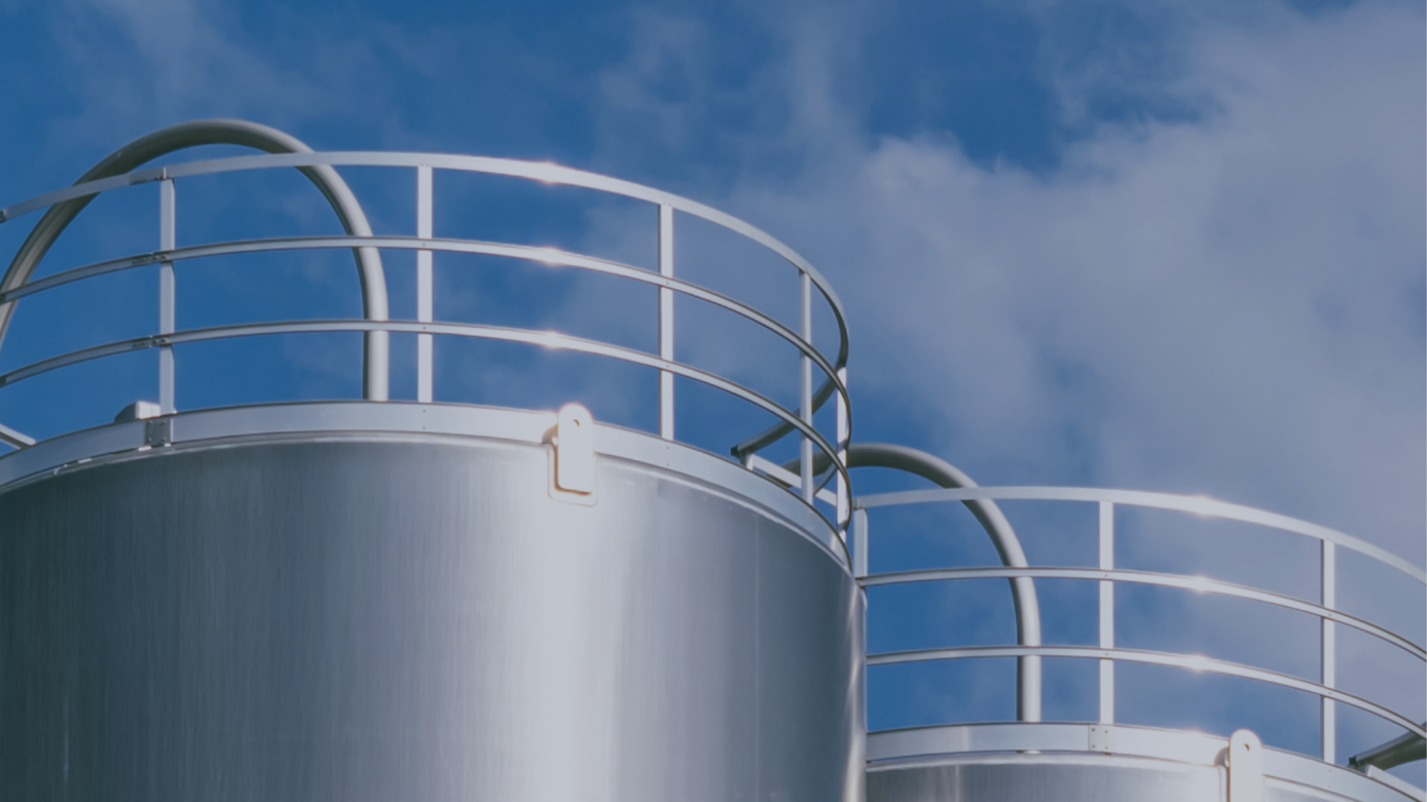 Two steel-colored hydrogen silos set against a blue sky with wispy clouds