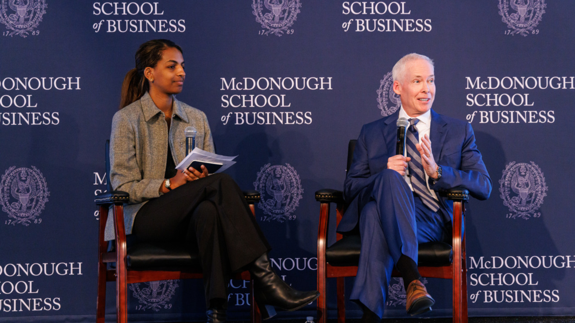 Georgetown McDonough blue and white background with two people seated on stage at Business of Health Summit