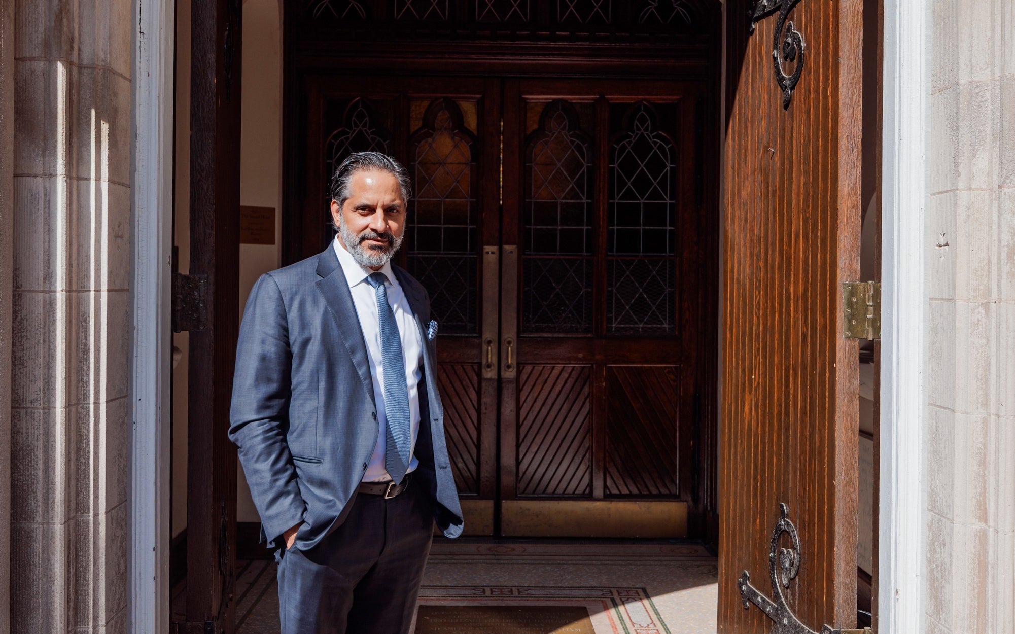Georgetown President Eduardo Peñalver stands in front of a chapel entrance in a suit